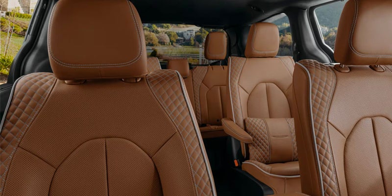 The interior of a vehicle, showing the brown leather seats with a diamond stitch pattern