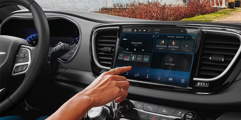 Hand touching the large touchscreen display in the Chrysler minivan's dashboard