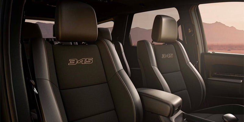 The front seats in a vehicle with the number "345" embroidered on the headrests
