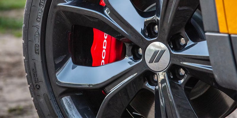 Close-up of black wheel, red brake caliper, and Dodge logo