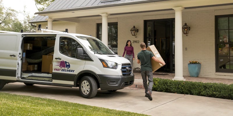 ford e-transit delivery person carrying a package from the van