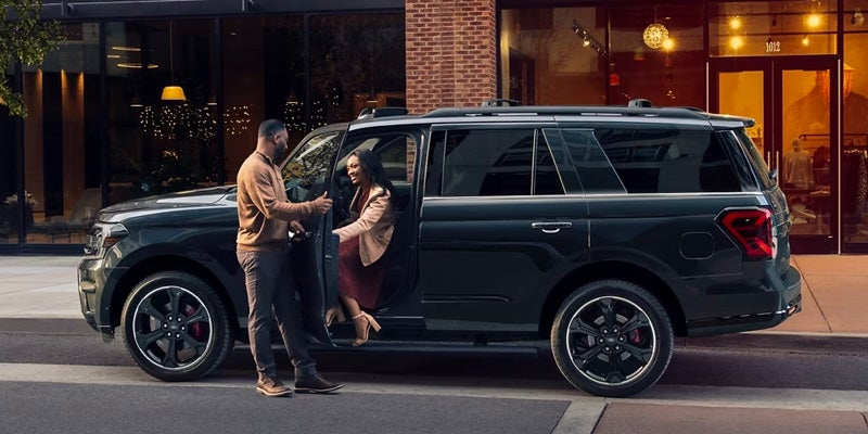 man helping woman out of a ford expedition