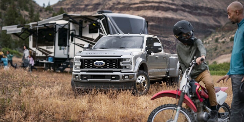 A man on a dirt bike near a Super Duty truck and RV.