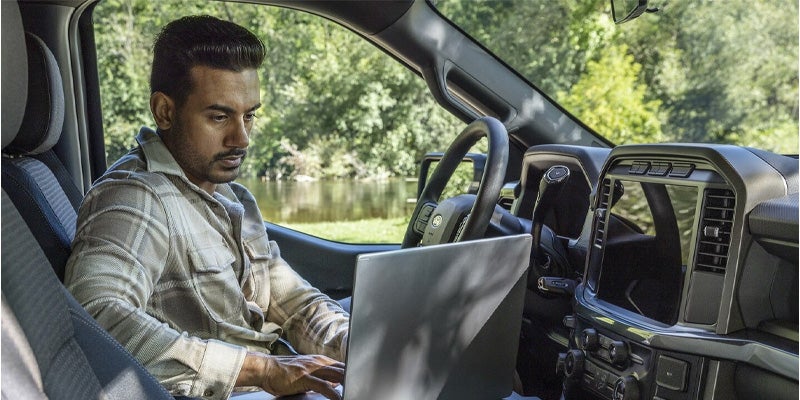 man working on a laptop inside a ford f-150 truck