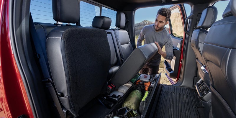A man loading items into the back seat of a Ford F-150 truck.