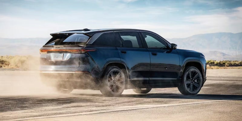 Dark blue Jeep Wagoneer S driving off-road, kicking up dust