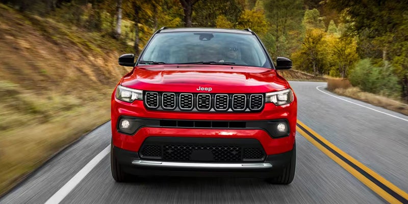 Front view of a red Jeep Compass SUV driving on a winding road