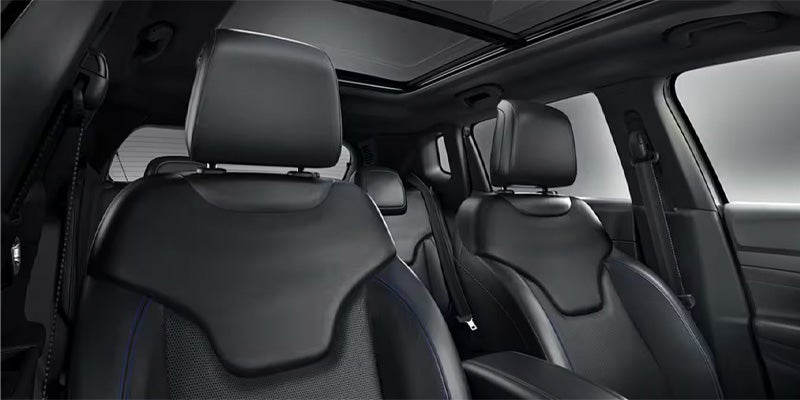 View of the black leather front seats and open sunroof in a Jeep Compass