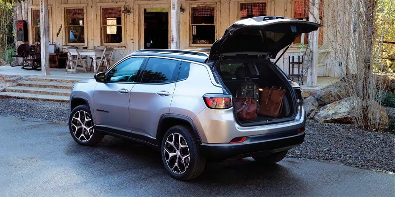 Silver Jeep Compass parked with its liftgate open, showing luggage inside