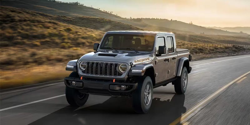Gray Jeep Gladiator Mojave pickup truck driving quickly on a highway at sunset