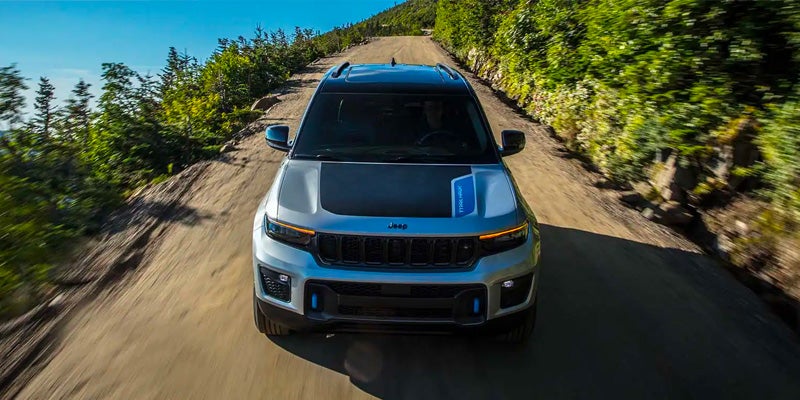 Silver Jeep Grand Cherokee Trailhawk driving on a dirt road