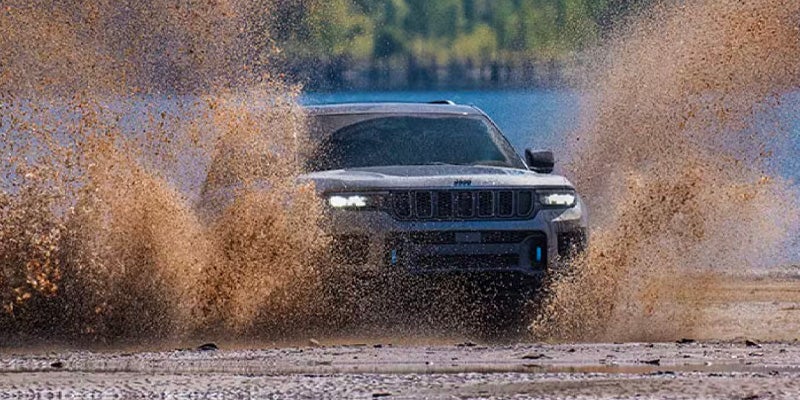 Dark gray Jeep Grand Cherokee splashing through a muddy area