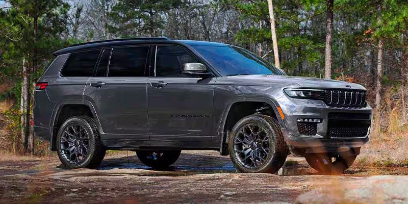 Dark gray Jeep Grand Cherokee L SUV with black wheels parked off-road