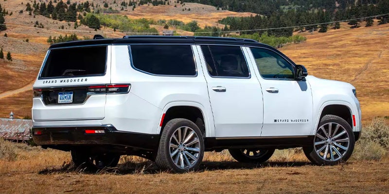 The rear view of a white Jeep Grand Wagoneer on a dirt road