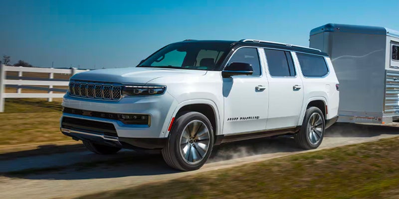 A white Jeep Grand Wagoneer tows a silver trailer