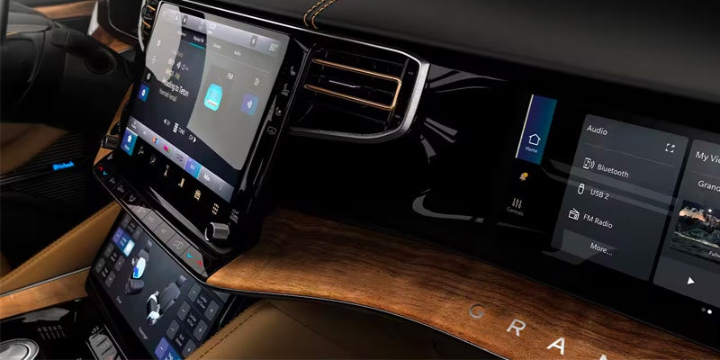 The Grand Wagoneer's dashboard with its multiple digital screens and wood paneling