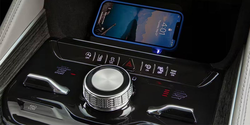 Vehicle center console with rotary dial, control buttons, and charging phone