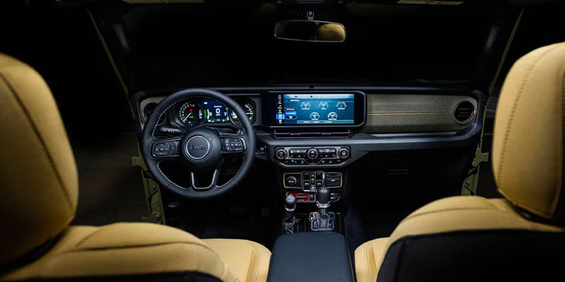 Interior view of the Jeep Wrangler dashboard with tan seats and infotainment screen