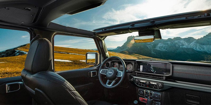 View from the open-top Jeep Wrangler interior showing a mountain landscape