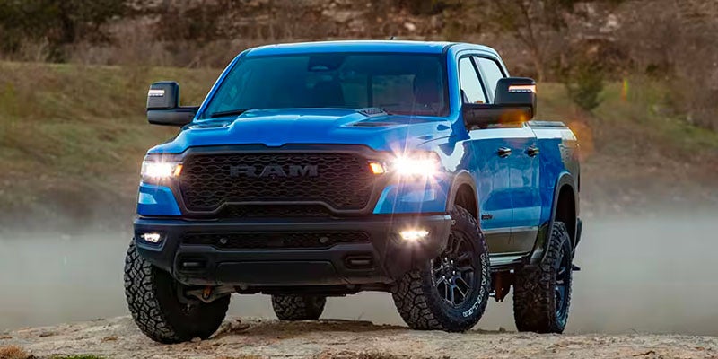 Blue RAM 1500 driving off-road with headlights on