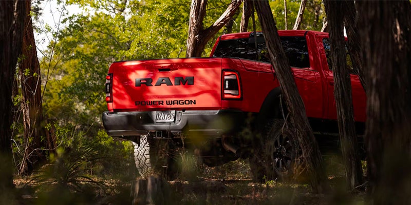 Red Ram Power Wagon rear view driving through a dense forest