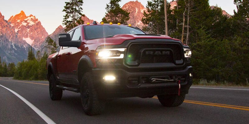 Red Ram Power Wagon driving on a road with mountains in the background