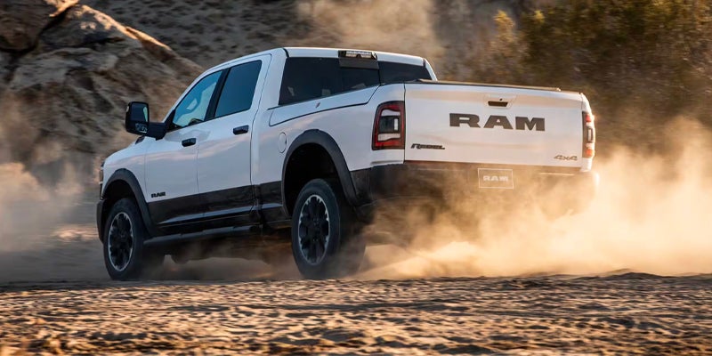White Ram Power Wagon driving away, kicking up dust on a dirt trail