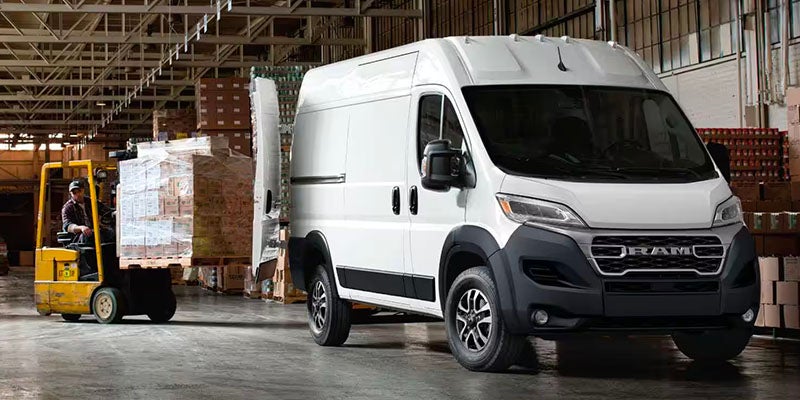White Ram ProMaster van parked in a warehouse, forklift moving pallets