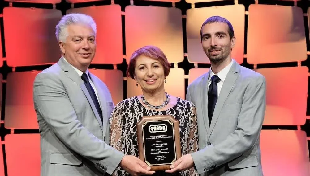 Igor, Yelena, and Alex Tovstanovsky on stage holding an NIADA award