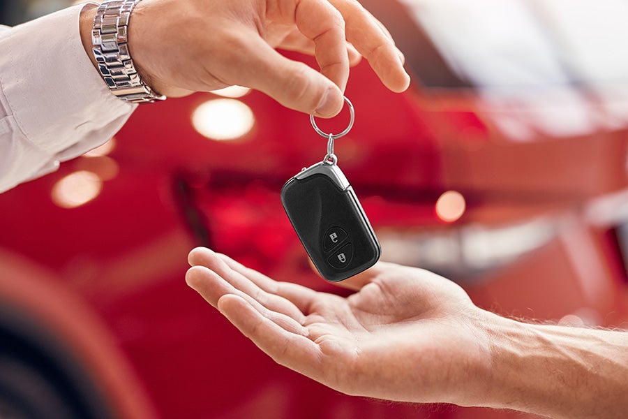 man giving car key to other man